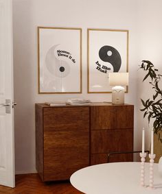 a living room with two paintings on the wall and a table in front of it