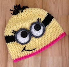 a crocheted hat with googly eyes on top of a wooden floor next to a pair of scissors