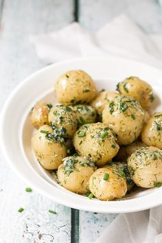 a white bowl filled with potatoes covered in herbs