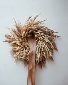 a dried wreath hanging on the wall with a brown ribbon tied around it's neck