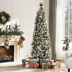 a decorated christmas tree in a living room next to a fireplace with presents under it