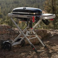 a portable grill on top of a rock with mountains in the background