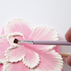 a person is painting a flower with a paintbrush on the tip of their finger