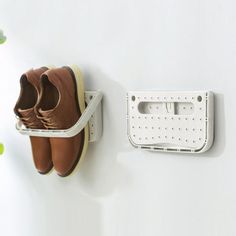 a pair of shoes hanging on a wall next to a shoe rack with two pairs of shoes