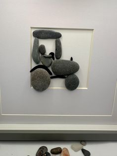 some rocks and stones are arranged in a frame on the wall next to each other