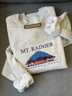 a white sweatshirt with the mt rainier logo on it is sitting on a couch