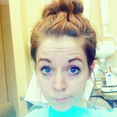 a woman with blue eyes is looking at the camera while in a dentist's office