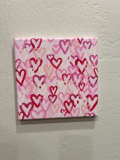 a pink and red painting with hearts on it's side hanging on a wall