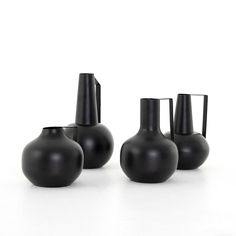 four black vases sitting next to each other on a white surface