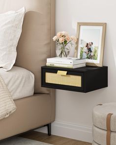 a nightstand with flowers and pictures on it next to a chair in a bedroom or living room