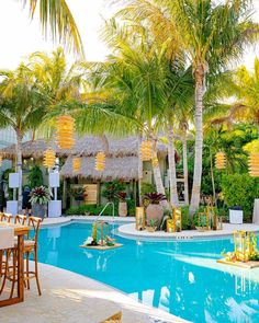 an outdoor dining area with tables and chairs next to a pool surrounded by palm trees