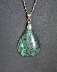 This jade is known among lapidary artists as being some of if not the best in the world for stone jewelry. This piece is a great example of the color and character of Maw Sit Sit which comes from Burma. While most all of it is nice I prefer the dark green/black examples of it which are more rare. Maw Sit Sit is made up of ureyite, jadeite and feldspar. This pendant is paired with stainless steel (bail and chain). In the global market we encourage you to shop local by supporting artists and small Green Stone Pendant Jewelry, Green Pendant Jewelry With Stones, Healing Malachite Gemstone Necklace, Oval Jade Jewelry With Natural Stones, Oval Jade Gemstone Beads Jewelry, Spiritual Malachite Jewelry With Natural Stones, Collectible Jade Pendant Jewelry, Collectible Jade Pendant Necklaces, Green Agate Stone Jewelry