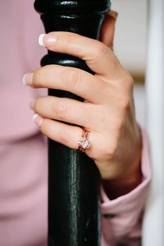 a woman's hand on top of a black pole with a diamond ring in it