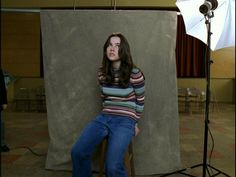 a woman sitting on a stool in front of a photo shoot with a camera and light