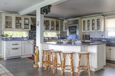 a large kitchen with white cabinets and wooden stools next to an island in the middle