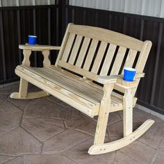 a wooden bench with two cups sitting on it's legs next to each other