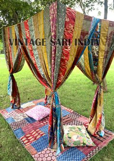 an open canopy covered in colorful fabrics on top of a patchwork blanket