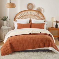 a bed with an orange comforter and pillows