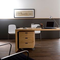 a wooden desk topped with a laptop computer sitting on top of a hard wood floor