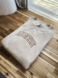 Us aunties/tias deserve a comfy and cozy sweatshirt too! Not an auntie?? Feel free to have a custom request for your sweatshirt! Just type it into the blank text box .🤍 This sweatshirt sports an athletic font that is giving cool aunt vibes. Throw this classic crew on and be ready to take on your exhausting day of being an auntie! Design measurements are roughly 7” long by 2.5” tall for sizes Small to XL. Sizes 2X - 4X have a design size of roughly 10" long by 4" tall. All sweatshirts are unisex One Word Sweatshirts, Auntie Era Sweatshirt, Auntie Embroidered Sweatshirt, Auntie Clothes, Cool Aunt Aesthetic, Auntie Outfits, Trending Sweatshirts, Aunt Aesthetic, Aunt Vibes