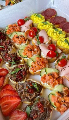 an assortment of appetizers in a box with strawberries and other fruits on the side