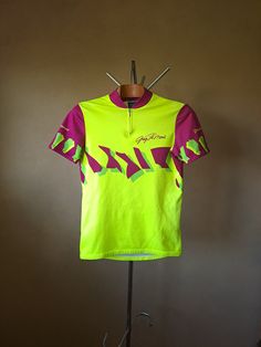 Vintage cycling jersey made in Italy by Tomasso in the early 90's. Features printed Greg LeMond signature above heart. About average thickness. Material is probably 100% polyester, maybe a bit of Nylon mixed in. Size would be a looser L in men's/XXL in women's by measurement, tag says 4. Condition 8/10: In very good shape, just small signs of previous use visible, like a couple of small pull remnants and slightly faded back. This cycling top has three pockets on the back and a short zipper on th Greg Lemond, Vintage Cycling Jersey, Vintage Cycling, Short Zipper, Cycling Tops, Ultimate Frisbee, Fluorescent Yellow, Yellow And Purple, Small Signs