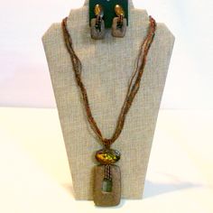 This Lovely Demi Parure Consists Of A Necklace And Matching Pierced Drop Earrings. The Set Is Fashioned In Different Shades Of Brown Seed Beads With A Dyed Shell Top At The Pendant And Earrings And What I Believe Is Lava Stone Drops. The Earrings Are Still On Their Original Card That Says Made In The Philippines. The Necklace Measures 24" In Length And The Pendant Has A Drop Of 3 7/8". The Earrings Feature A Post Back For Pierced Ears And Are 2" In Length. Bohemian Brown Jewelry With Matching Earrings, Earthy Beaded Dangle Jewelry, Handmade Brown Rectangular Jewelry, Bohemian Brown Rectangular Jewelry, Earthy Fair Trade Jewelry As Gift, Earthy Fair Trade Jewelry Gift, Dangle Jewelry With Colorful Beads, Brown Dangle Jewelry With Colorful Beads, Brown Fair Trade Jewelry For Festivals