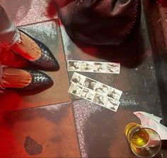 a pair of red shoes sitting on top of a table next to a bottle of wine