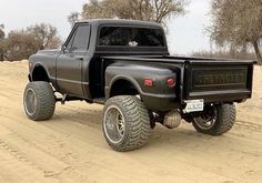 a black pickup truck driving down a dirt road