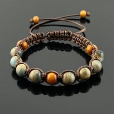 "Indulge in the earthy elegance of our woven braided bracelet.  Crafted using the intricate square knot technique, this bracelet showcases a harmonious blend of warm hues contained in the beige nylon satin cord, and ceramic and wood beads. Each knot and twist speaks of artisanal craftsmanship, making it a timeless addition to your collection, bringing style and balance to your everyday look. This braided bracelet is designed to be adjustable, ensuring a perfect fit for wrist sizes ranging from 7 Spiritual Brown Beaded Bracelets With Adjustable Cord, Brown Macrame Braided Bracelet In Waxed Cord, Brown Macrame Jewelry For Friendship, Braided Bracelets With Round Beads As Gift, Adjustable Brown Macrame Beaded Bracelets, Adjustable Hand-strung Brown Braided Bracelets, Brown Spiritual Braided Bracelets For Friendship, Spiritual Brown Macrame Braided Bracelets, Brown Macrame Beaded Bracelets For Friendship