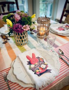 the table is set with plates, silverware and flowers