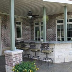 an outdoor bar with four chairs on the front porch and one sitting in the back