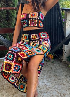 a woman in a multicolored crochet skirt and crop top posing for the camera