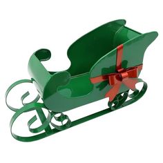 a green christmas sleigh with red ribbon and bow on it's side