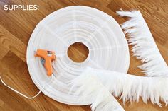 the supplies needed to make this diy feather wreath are laid out on the floor