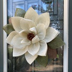 a white flower is hanging on the front door window sill with burlocks