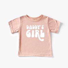 "Attention all parents and grandparents! Get ready to celebrate the special bond between father and daughter with our adorable 'Daddy's Girl' T-Shirt. This charming t-shirt is the perfect gift for Father's Day, birthdays, or any occasion where you want to show your love and appreciation. Our 'Daddy's Girl' t-shirt is designed with love and attention to detail. The vibrant and playful design features the words \"Daddy's Girl\" in a whimsical font, surrounded by cute elements that capture the esse Playful Father's Day T-shirt For Family, Playful Pink T-shirt With Slogan, Father's Day Pink T-shirt With Letter Print, Cute Summer T-shirt For Parenting, Cute Cotton T-shirt With Name Print, Cute Pink T-shirt With Funny Text, Playful Cotton Family T-shirt, Unisex Pink Playful T-shirt, Cute Cotton T-shirt For Family