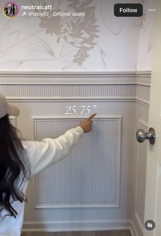 a woman is pointing to the wall with numbers on it