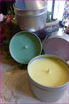 three tins filled with candles sitting on top of a table