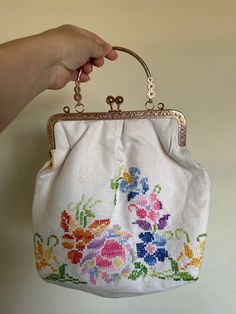 a hand holding a white purse with flowers on it