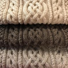 four knitted blankets stacked on top of each other