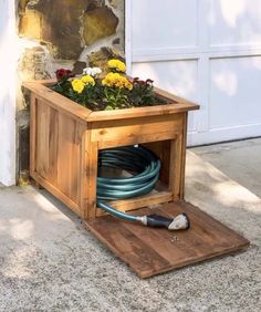 a planter box with flowers in it and a hose connected to the ground outside