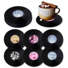 six black records with different designs on them and a cup of hot chocolate in the middle