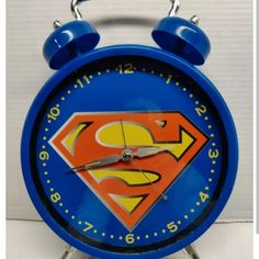 a blue alarm clock with superman logo on it's face and the time is 11 00