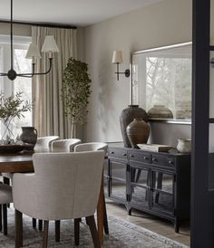 a dining room table with chairs and a vase on top of it in front of a window