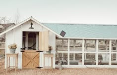 a chicken coop with an open door and windows on the side, in front of a barn