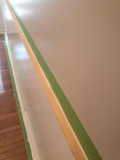 an empty hallway with green tape on the wall and wood flooring in front of it