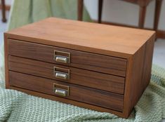 a wooden box sitting on top of a green blanket