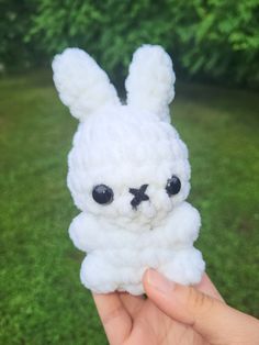 a hand holding a small white stuffed animal