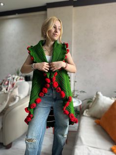 a woman standing in a living room wearing a green shawl with red flowers on it